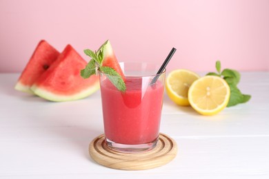 Photo of Tasty watermelon drink in glass, mint and fresh fruits on white wooden table