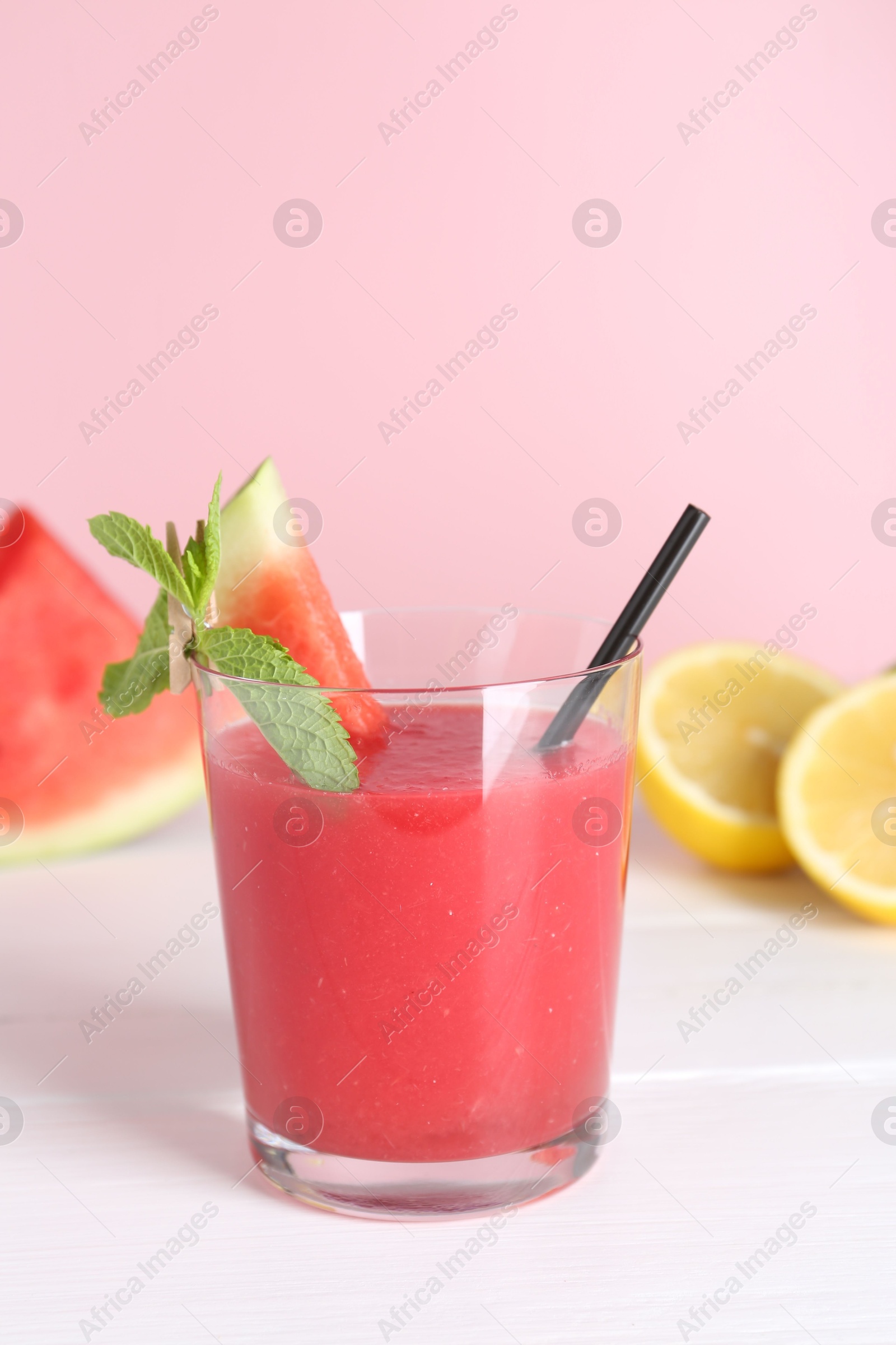 Photo of Tasty watermelon drink in glass, mint and fresh fruits on white wooden table