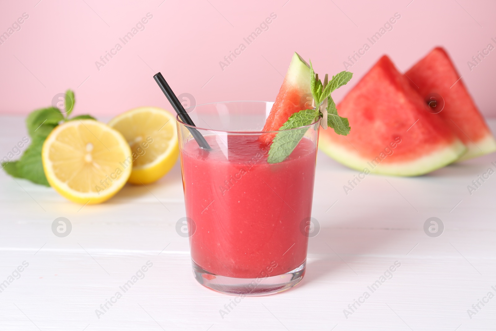 Photo of Tasty watermelon drink in glass, mint and fresh fruits on white wooden table