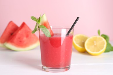 Photo of Tasty watermelon drink in glass, mint and fresh fruits on white wooden table