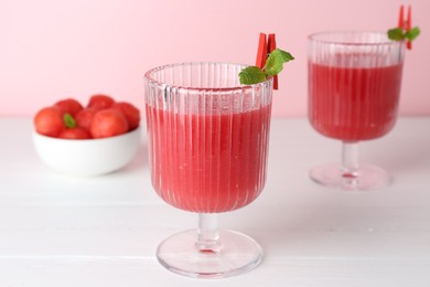 Photo of Tasty watermelon drink in glasses and fresh fruit on white wooden table, closeup