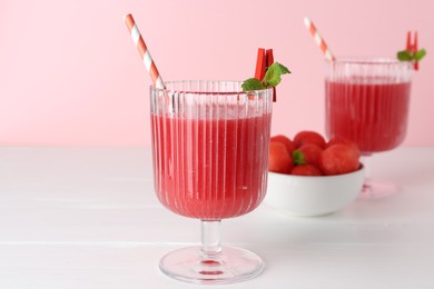 Photo of Tasty watermelon drink in glasses and fresh fruit on white wooden table, closeup