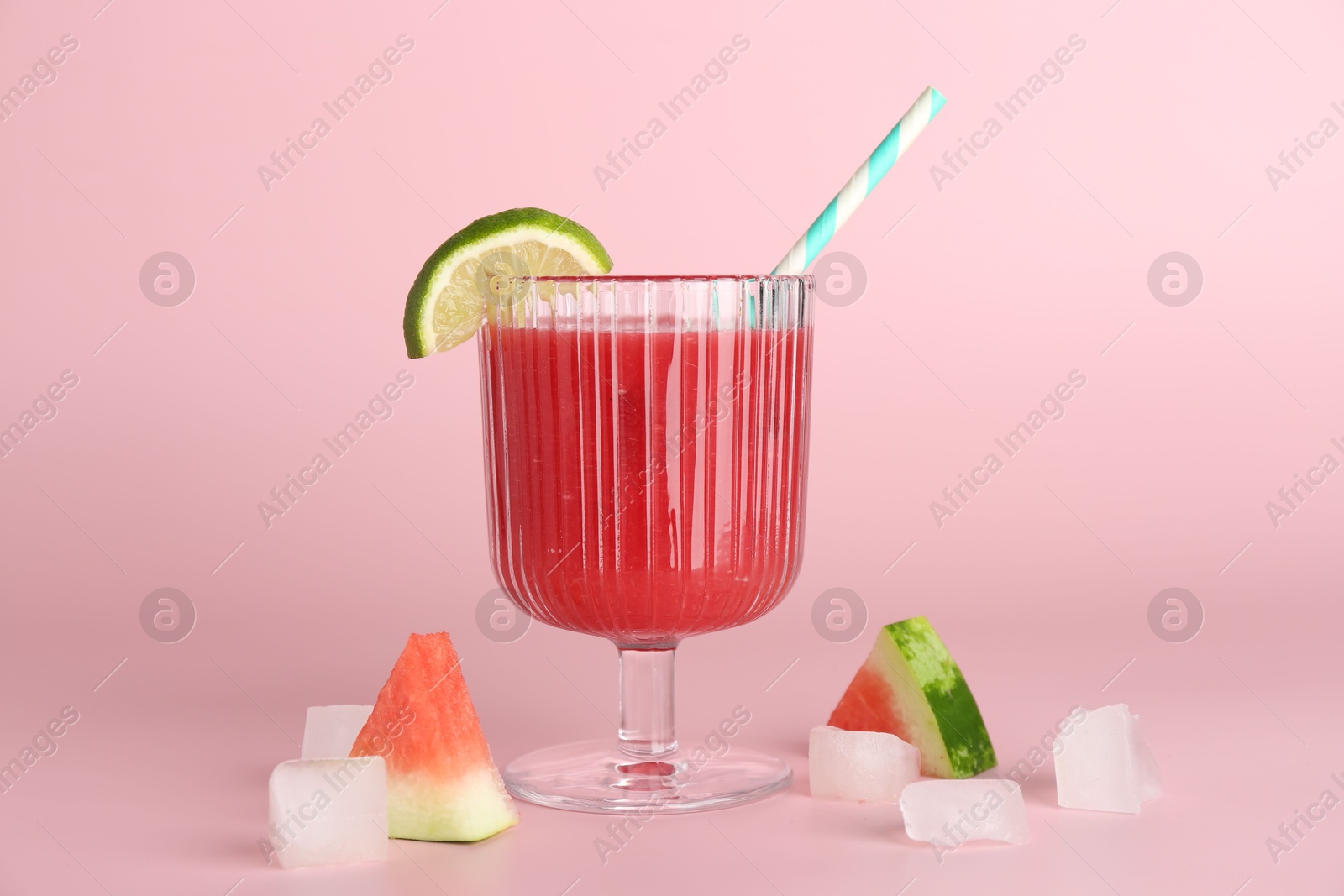 Photo of Tasty watermelon drink in glass, fresh fruits and ice cubes on pink background