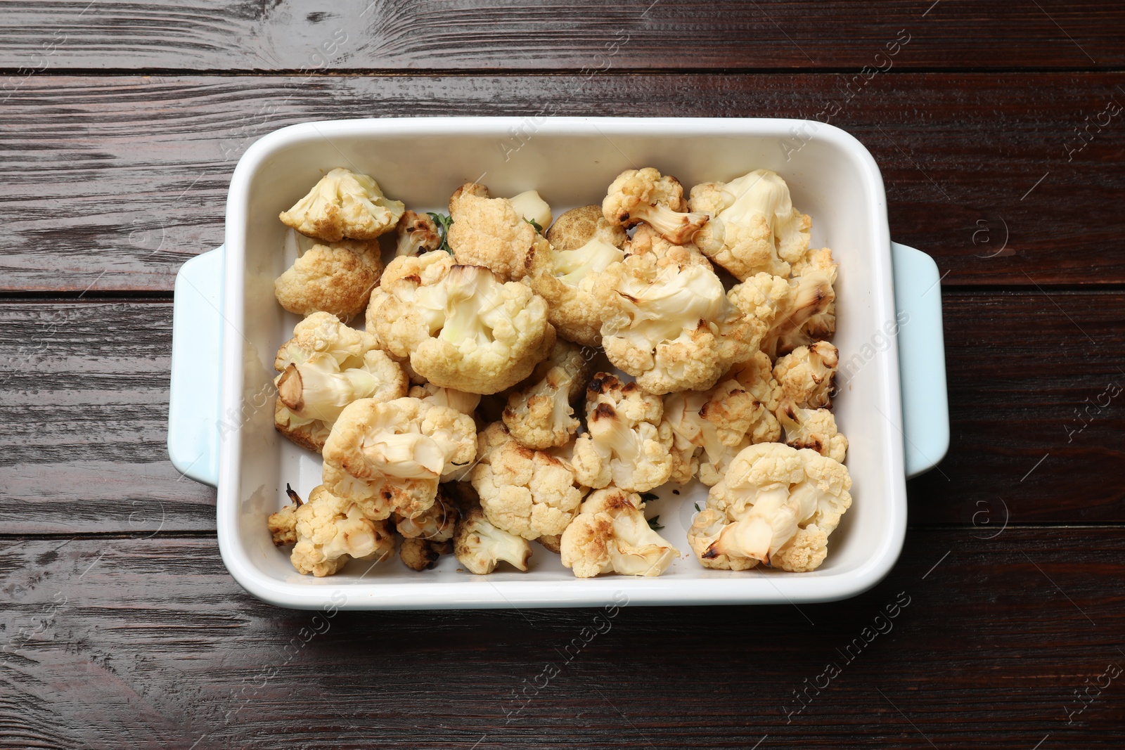 Photo of Baked cauliflower in baking dish on wooden table, top view