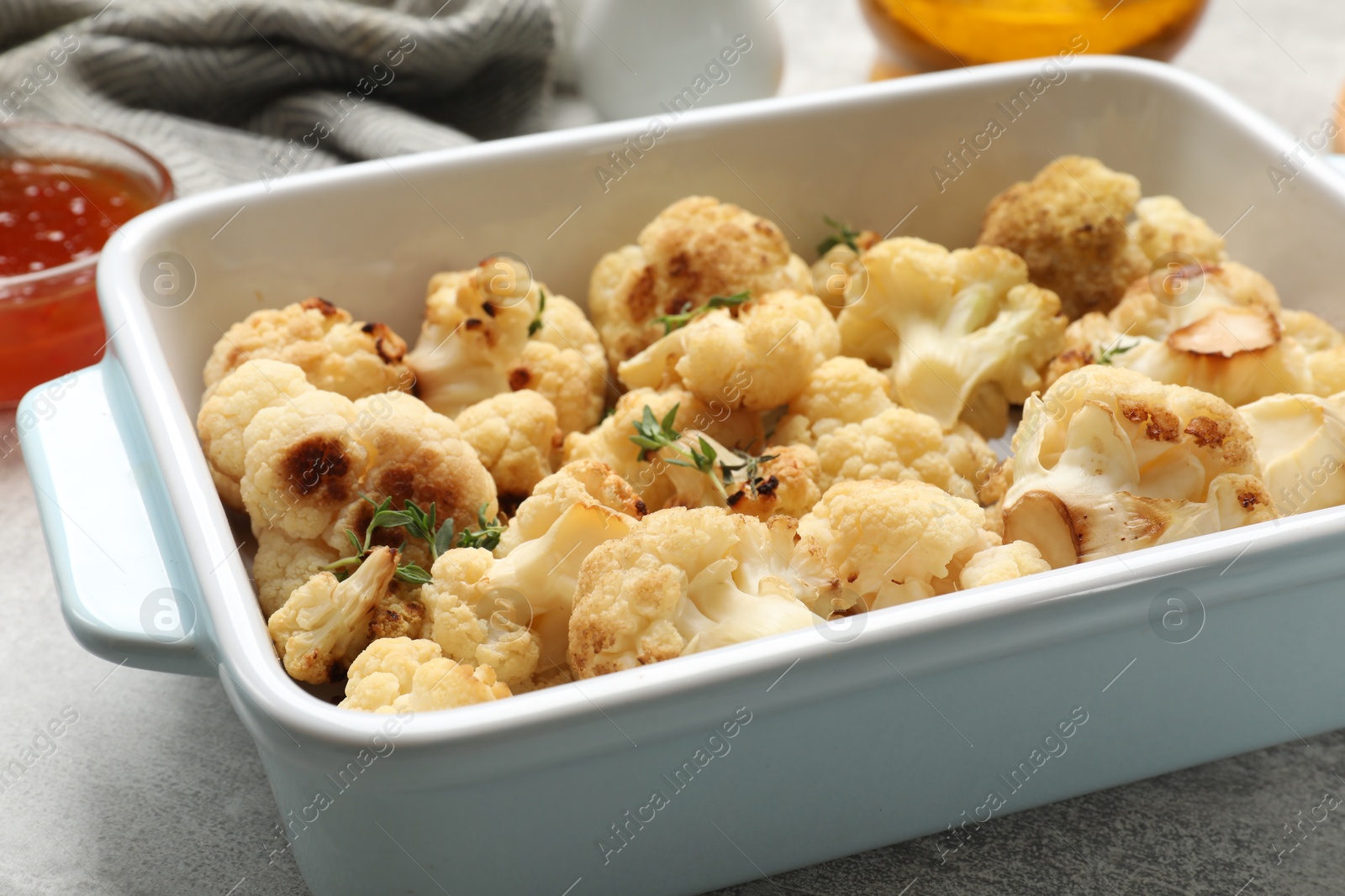 Photo of Baked cauliflower in baking dish on light grey table, closeup