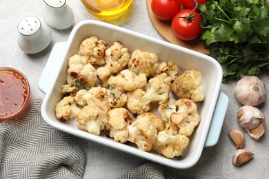 Baked cauliflower, products and sauce on light grey table, flat lay