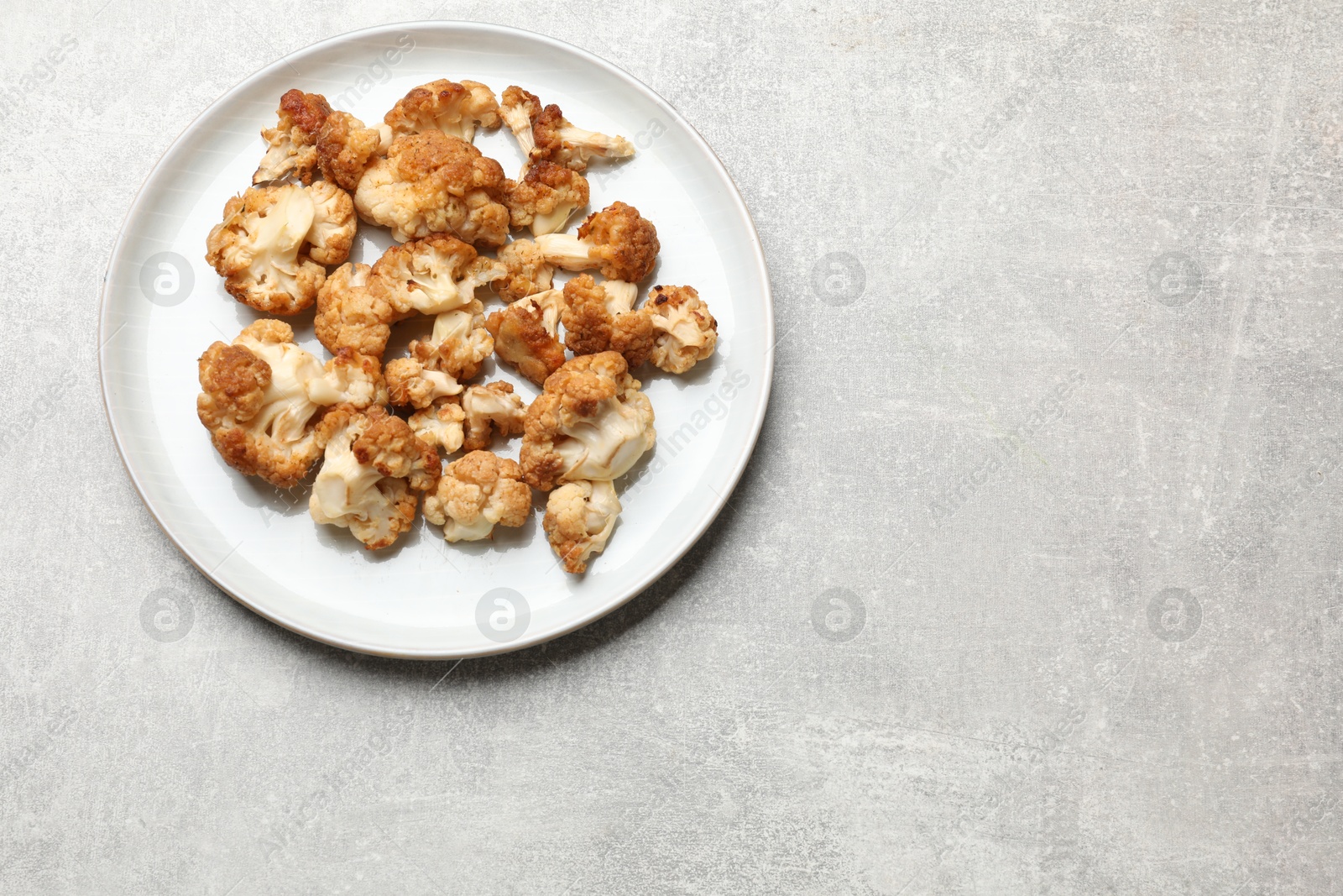 Photo of Baked cauliflower on light grey table, top view. Space for text