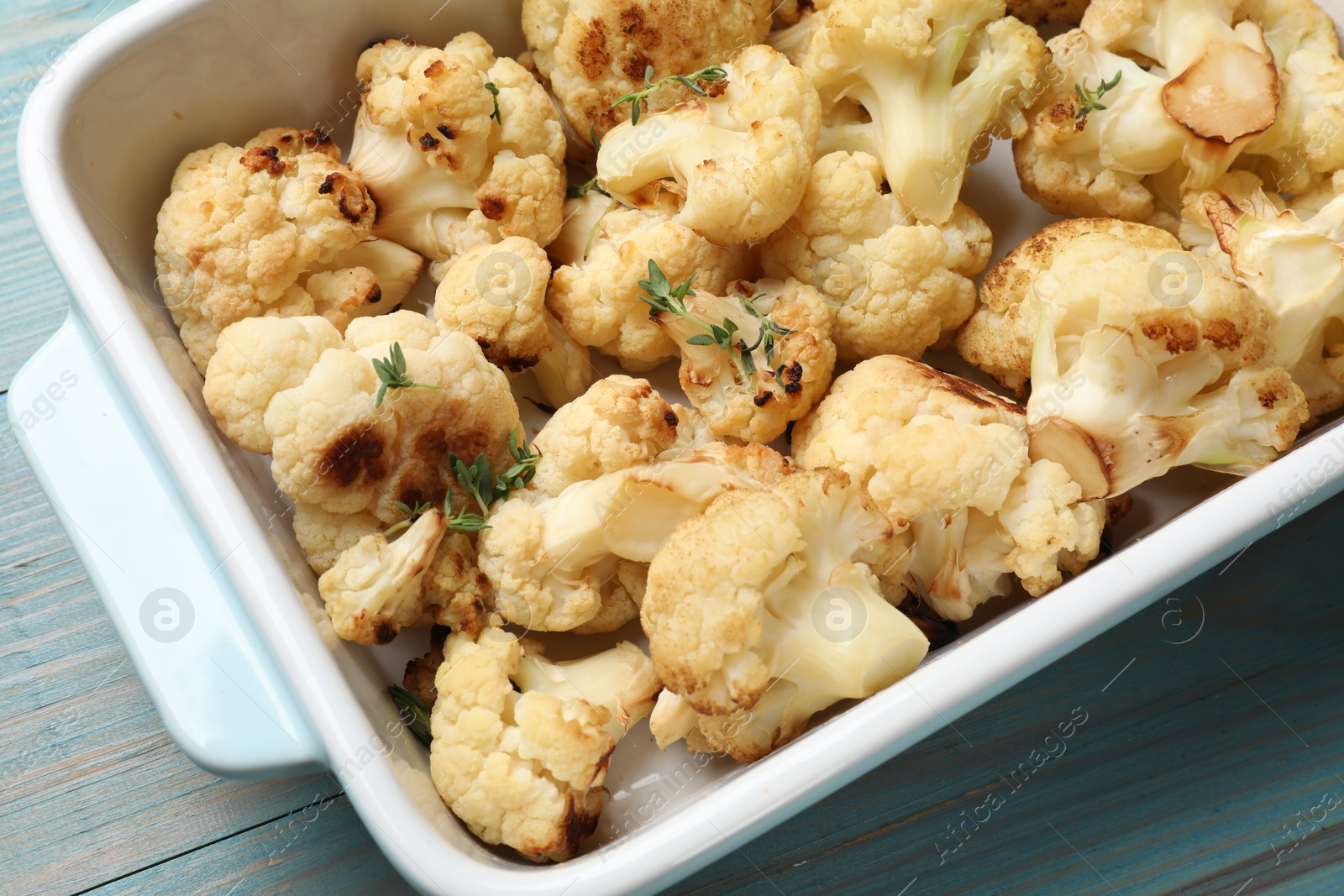 Photo of Baked cauliflower in baking dish on light blue wooden table, top view