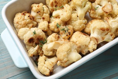 Photo of Baked cauliflower in baking dish on light blue wooden table, top view