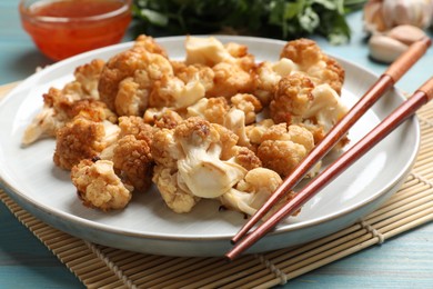 Photo of Baked cauliflower, products and sauce on light blue wooden table, closeup