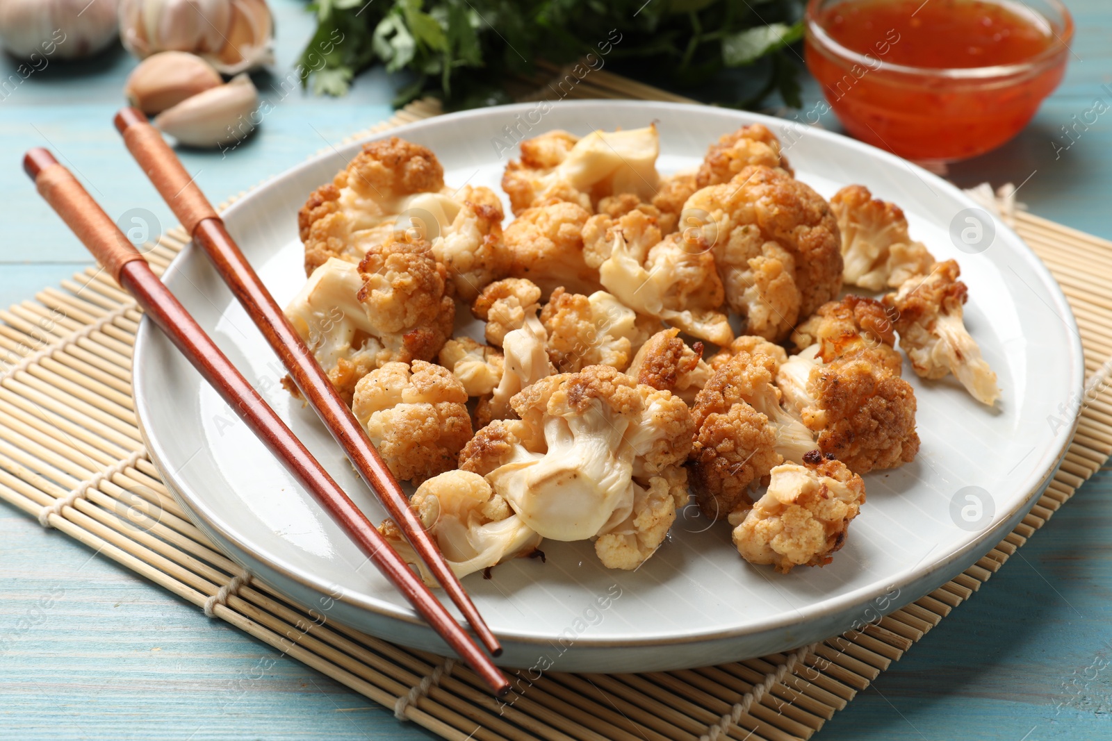 Photo of Baked cauliflower, products and sauce on light blue wooden table