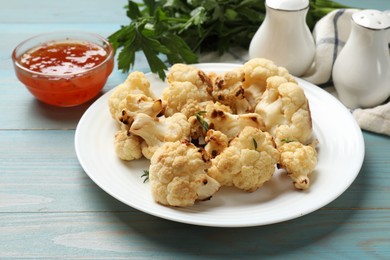 Photo of Baked cauliflower and sauce on light blue wooden table