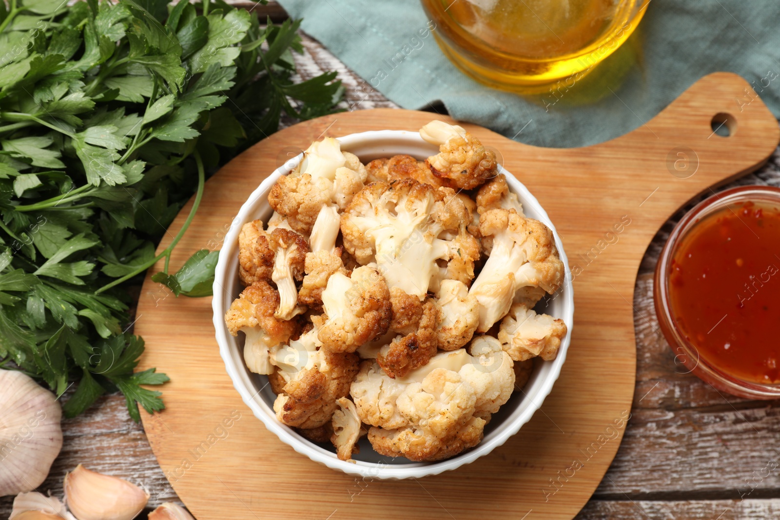 Photo of Baked cauliflower, sauce and products on wooden table, flat lay