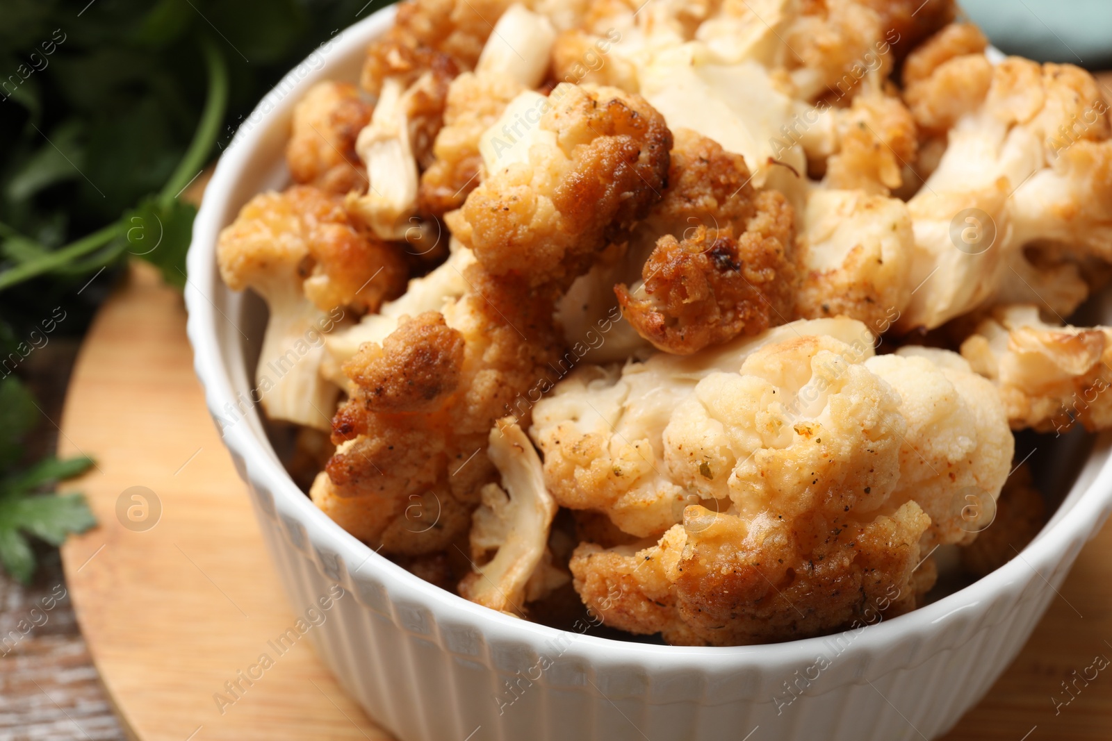 Photo of Baked cauliflower in bowl on wooden table, closeup