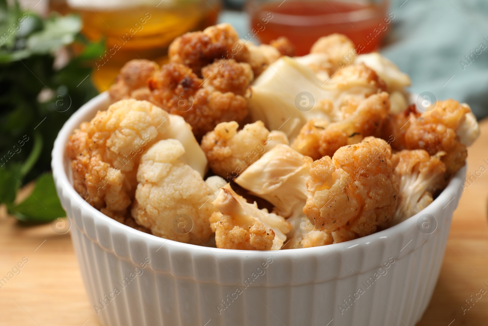 Photo of Baked cauliflower and products on wooden table, closeup