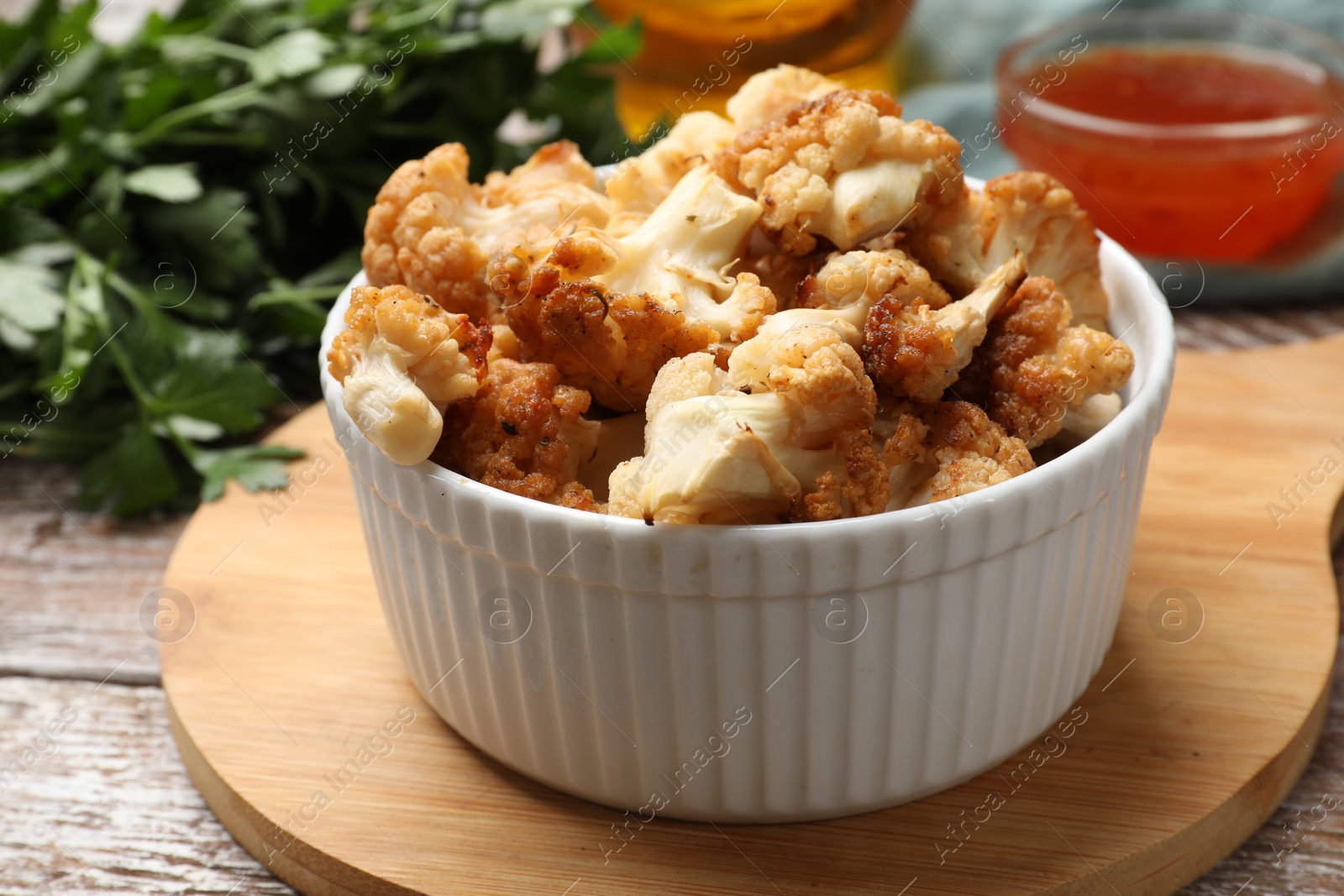 Photo of Baked cauliflower, sauce and products on wooden table