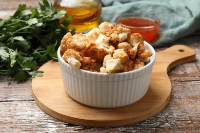 Photo of Baked cauliflower, sauce and products on wooden table