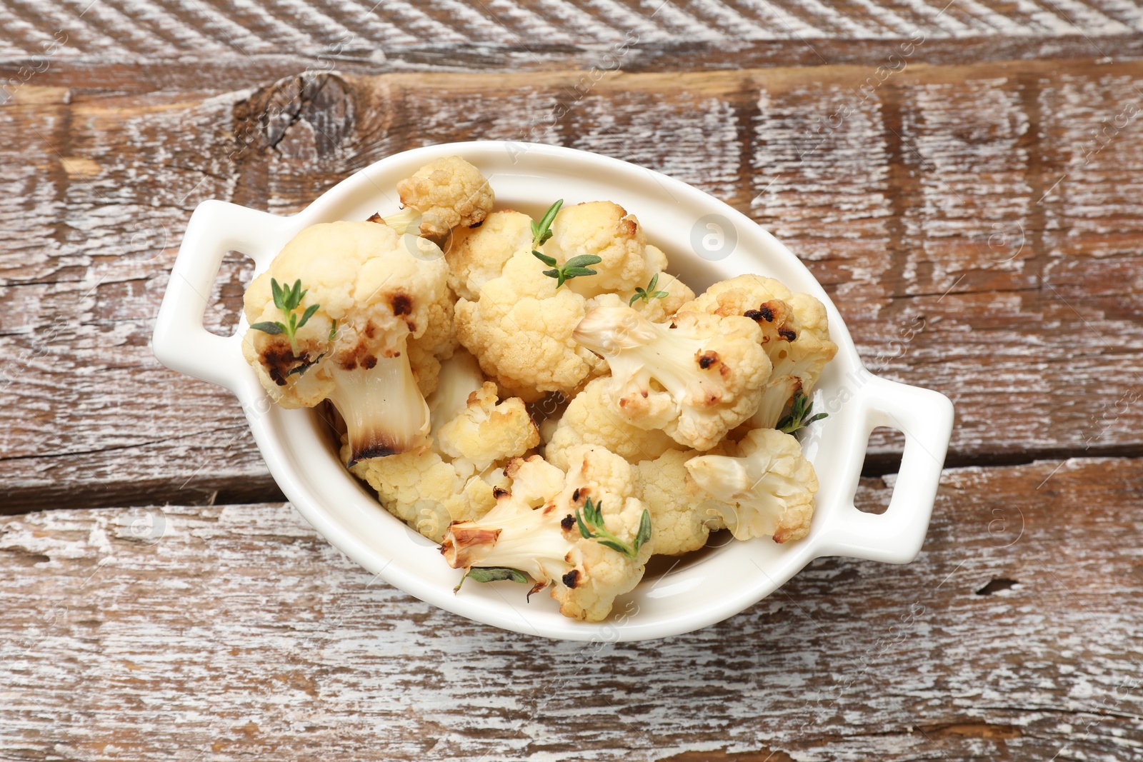 Photo of Baked cauliflower in baking dish on wooden table, top view