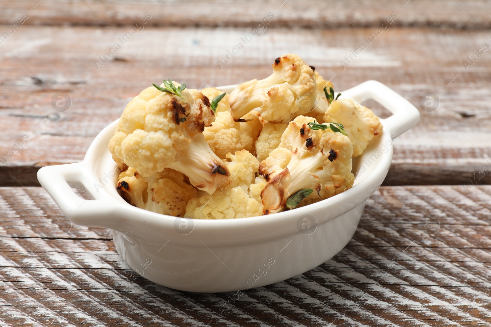 Photo of Baked cauliflower in baking dish on wooden table