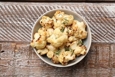 Baked cauliflower in bowl on wooden table, top view