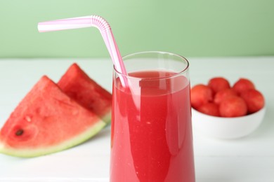 Photo of Tasty watermelon drink in glass and fresh fruit on white table, closeup