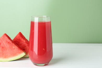 Photo of Tasty watermelon drink in glass and fresh fruit on white wooden table. Space for text