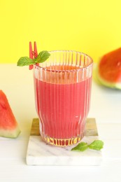 Photo of Tasty watermelon drink in glass and fresh fruit on white table, closeup