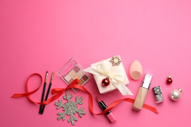 Photo of Flat lay composition with makeup products and Christmas decor on pink background. Space for text