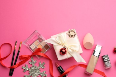 Photo of Flat lay composition with makeup products and Christmas decor on pink background. Space for text