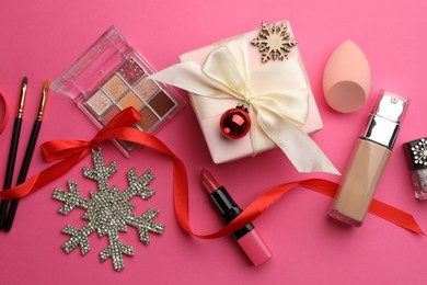 Flat lay composition with makeup products and Christmas decor on pink background