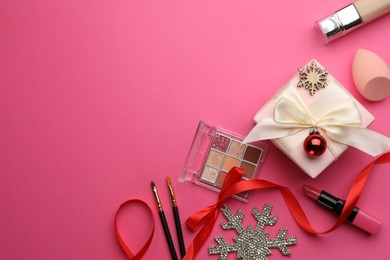 Photo of Flat lay composition with makeup products and Christmas decor on pink background. Space for text