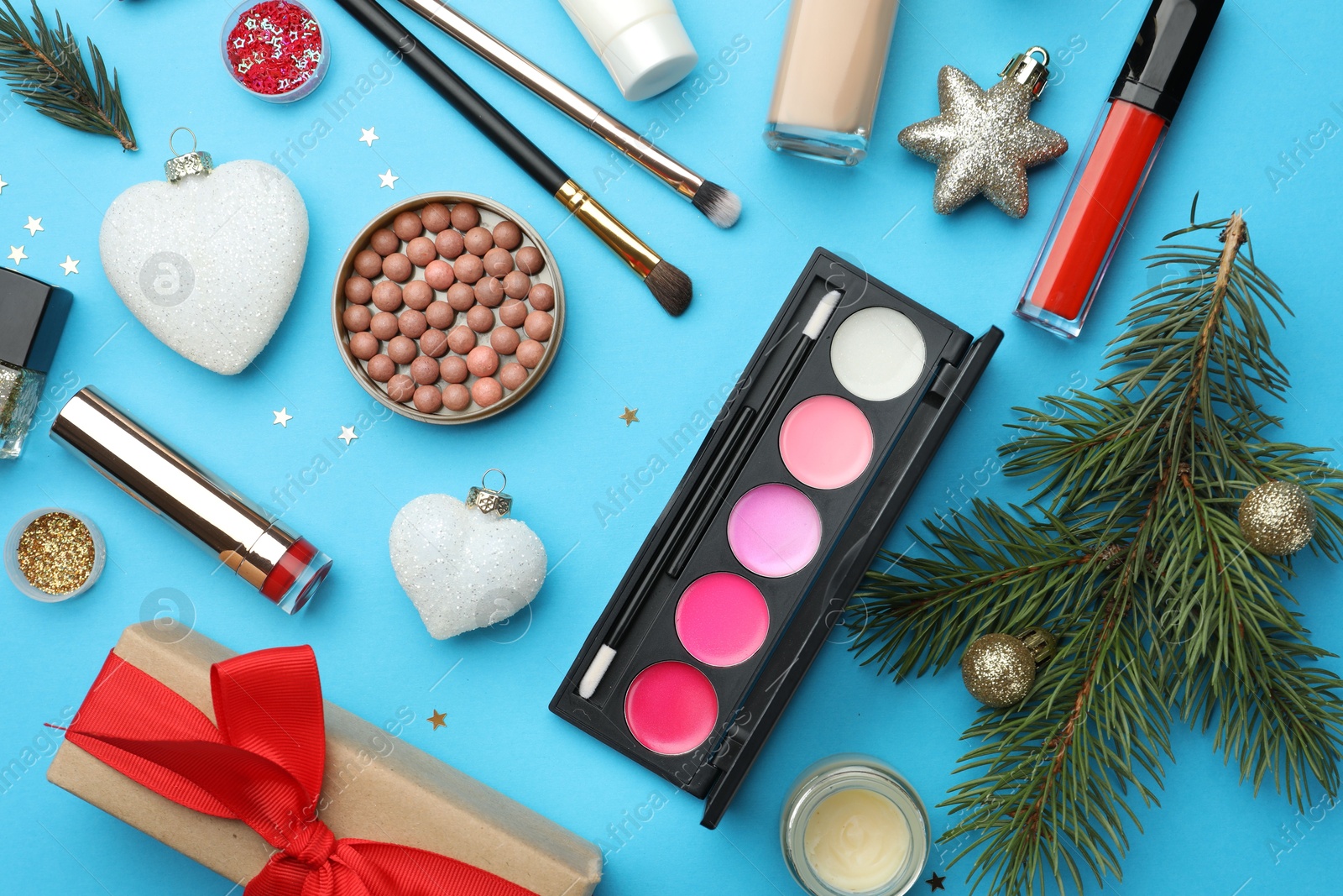 Photo of Flat lay composition with makeup products and Christmas decor on light blue background