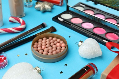 Photo of Different makeup products and Christmas decor on light blue background, closeup