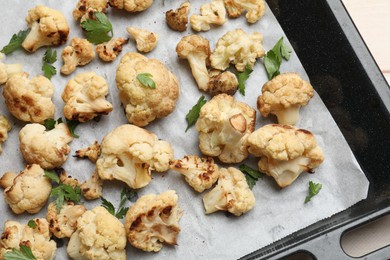 Photo of Baking tray with tasty baked cauliflower and parsley on table, top view