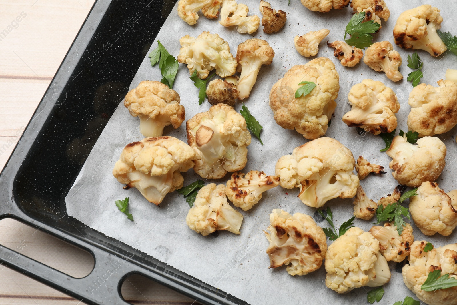 Photo of Baking tray with tasty baked cauliflower and parsley on table, top view