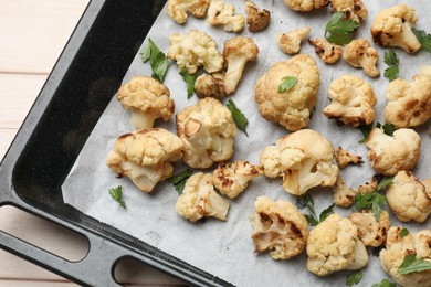 Baking tray with tasty baked cauliflower and parsley on table, top view