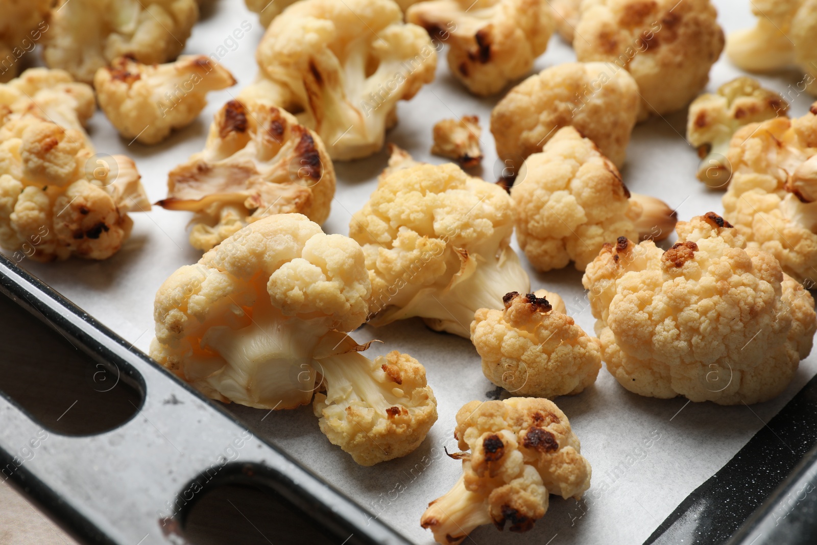 Photo of Tasty baked cauliflower on baking tray, closeup