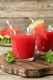 Photo of Tasty watermelon drink in glasses, fresh fruit and mint on wooden table, closeup