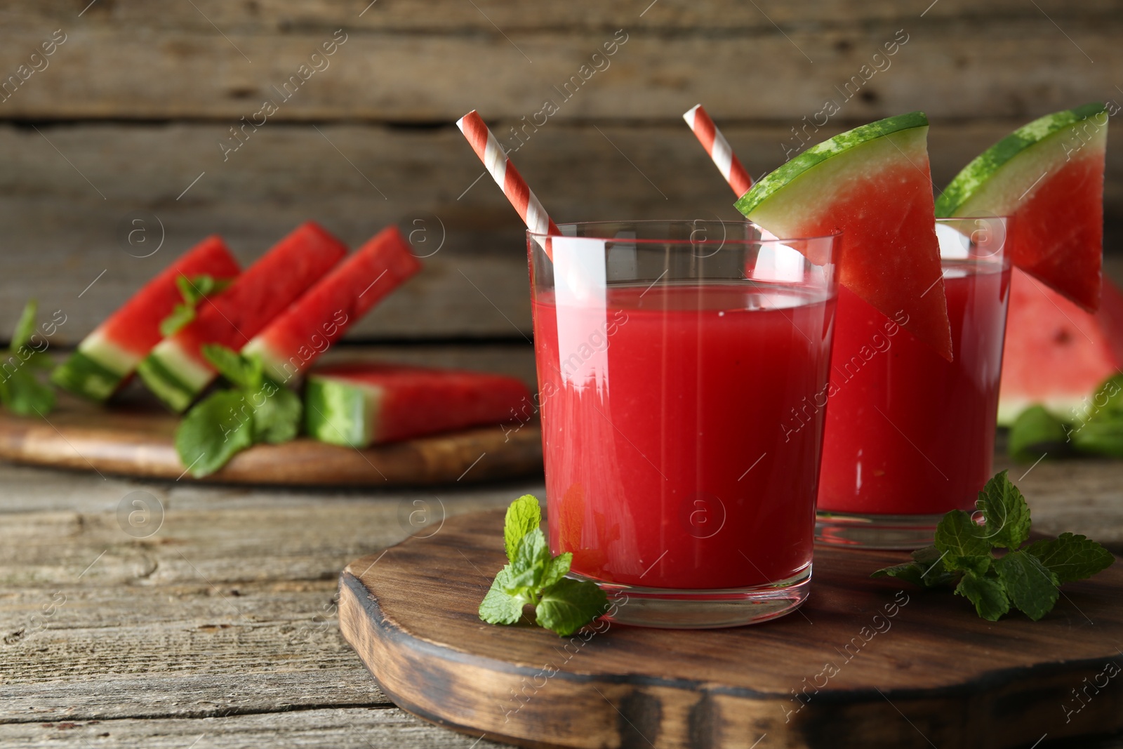 Photo of Tasty watermelon drink in glasses, fresh fruit and mint on wooden table