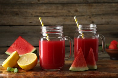 Photo of Tasty watermelon drink in mason jars and fresh fruits on wooden table