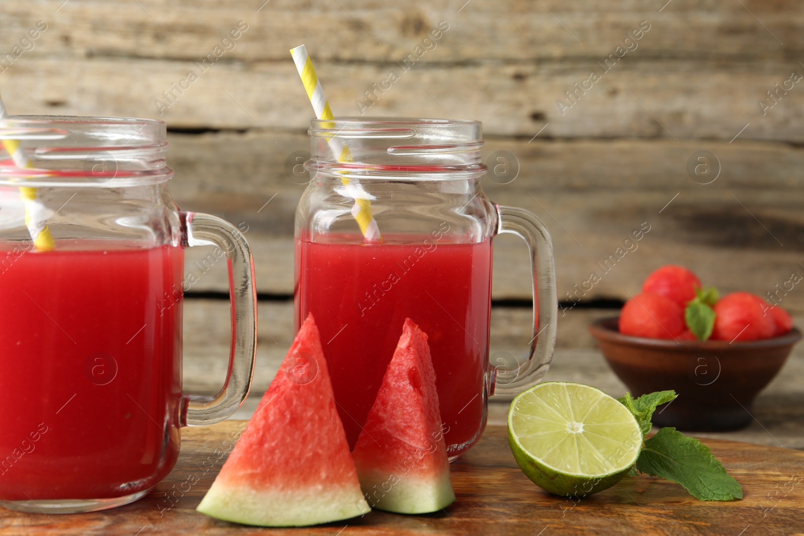 Photo of Tasty watermelon drink in mason jars and fresh fruits on wooden table, closeup