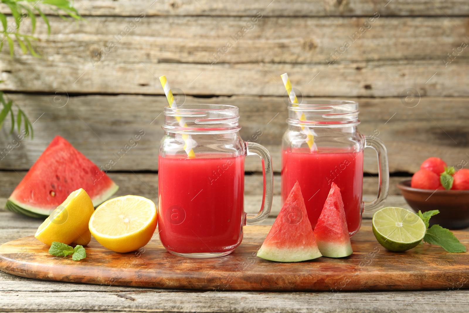 Photo of Tasty watermelon drink in mason jars and fresh fruits on wooden table