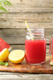 Photo of Tasty watermelon drink in mason jar and fresh fruits on wooden table