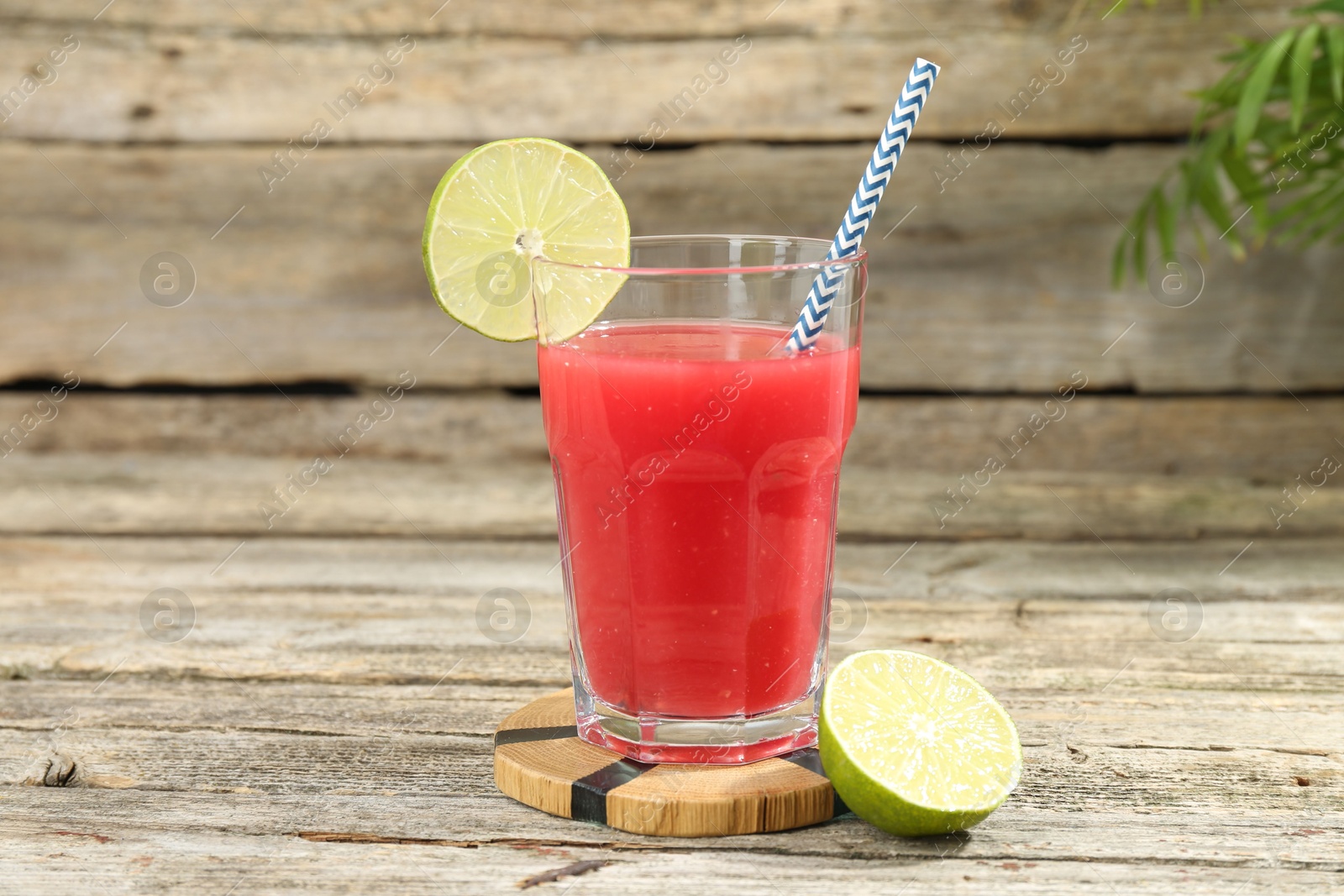 Photo of Tasty watermelon drink in glass and lime on wooden table