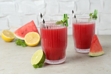 Photo of Delicious watermelon drink in glasses, fresh fruits and mint on light table