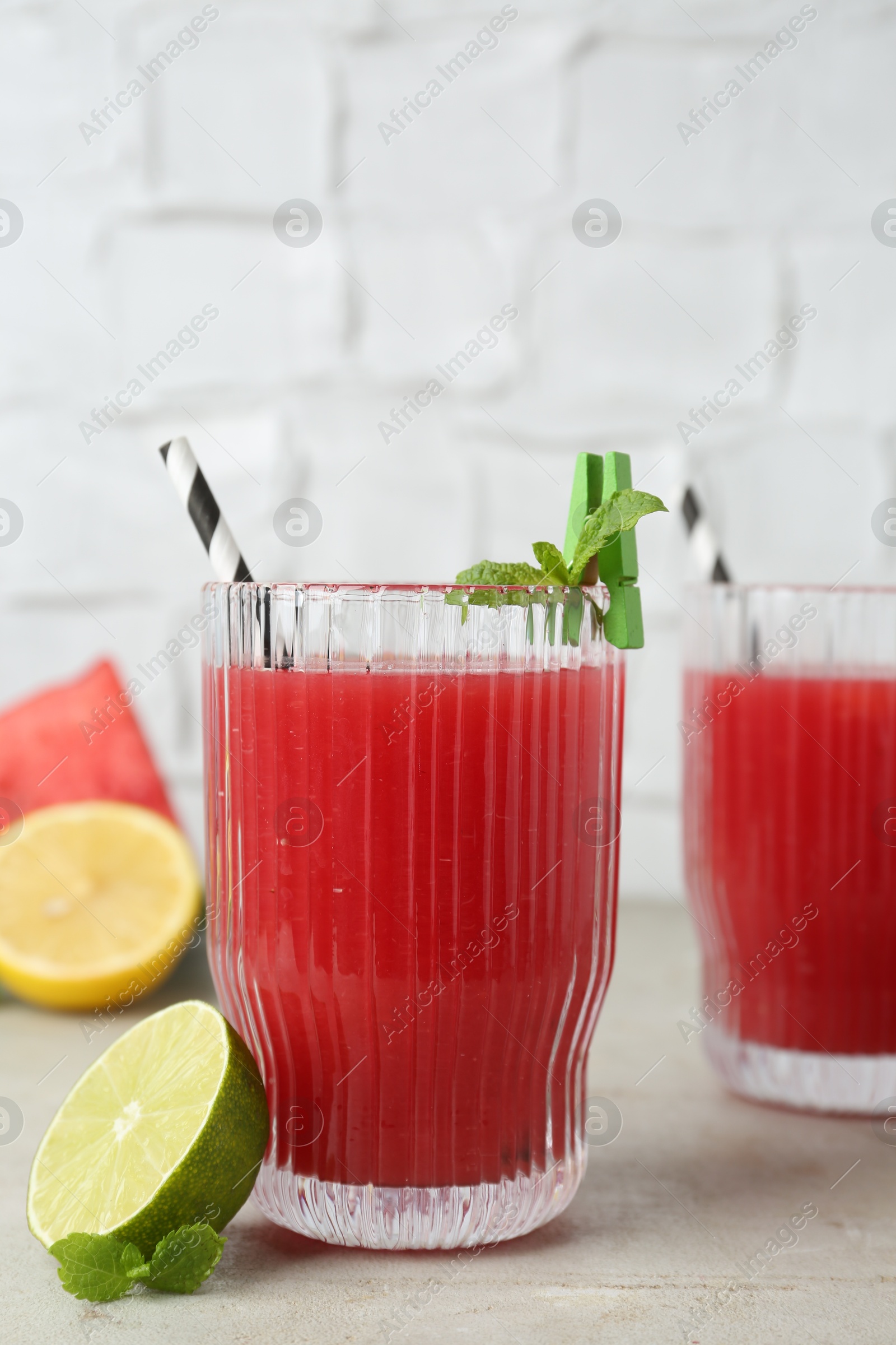 Photo of Delicious watermelon drink in glasses, fresh fruits and mint on light table