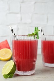 Photo of Delicious watermelon drink in glasses, fresh fruits and mint on light table