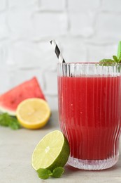 Photo of Delicious watermelon drink in glass, fresh fruits and mint on light table, closeup