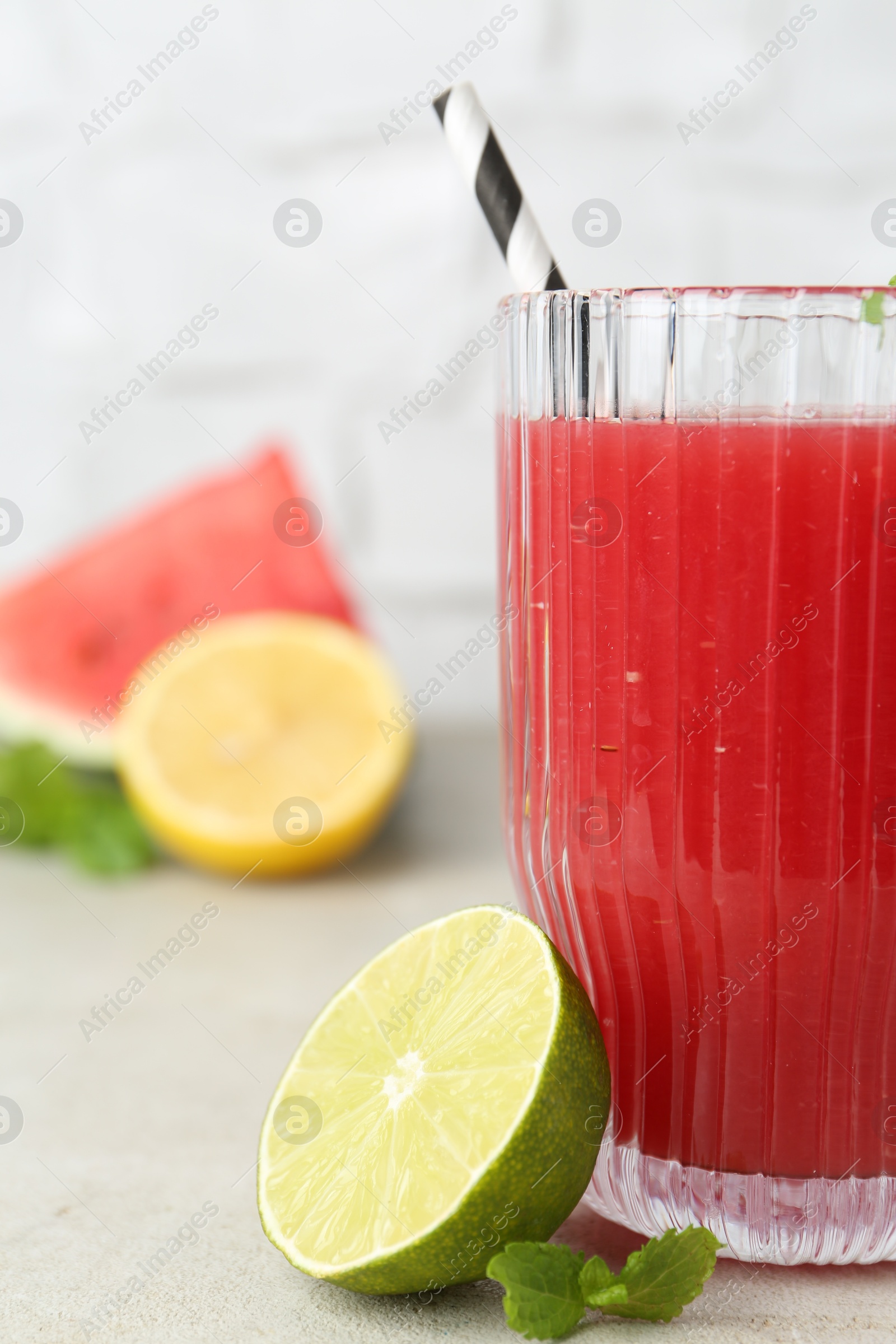 Photo of Delicious watermelon drink in glass, fresh fruits and mint on light table, closeup