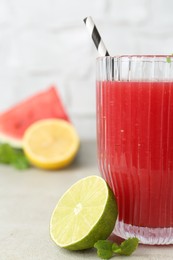 Photo of Delicious watermelon drink in glass, fresh fruits and mint on light table, closeup